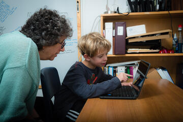 Teacher working with a student using a laptop